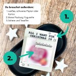Karte mit dem Text „All I want for Christmas is You“ liegt auf schwarzer Schale, daneben weiße Sterne. Auf dem Bild steht: „Du brauchst außerdem: 1. weißes Papier oder Karton, 2. kleine Packung Yogurette, 3. Schere und Tesafilm“. Perfekte Anleitung für ein kleines Geschenk zu Weihnachten.