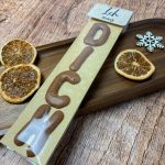 Fertig gebasteltes „Ich mag dich“-Geschenk mit Süßigkeiten in Buchstabenform. Gelbes Sternenpapier und winterliche Holzdeko schaffen eine warme Weihnachtsstimmung – perfekte Adventskalenderidee zum Selbermachen.