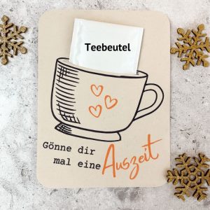 Karte mit einer Teetasse und der Aufschrift „Gönne dir mal eine Auszeit“, oben steckt ein Teebeutel. Dekoriert mit goldenen Schneeflocken. Perfekte kleine Aufmerksamkeit oder Geschenk zu Weihnachten zum Selbermachen.