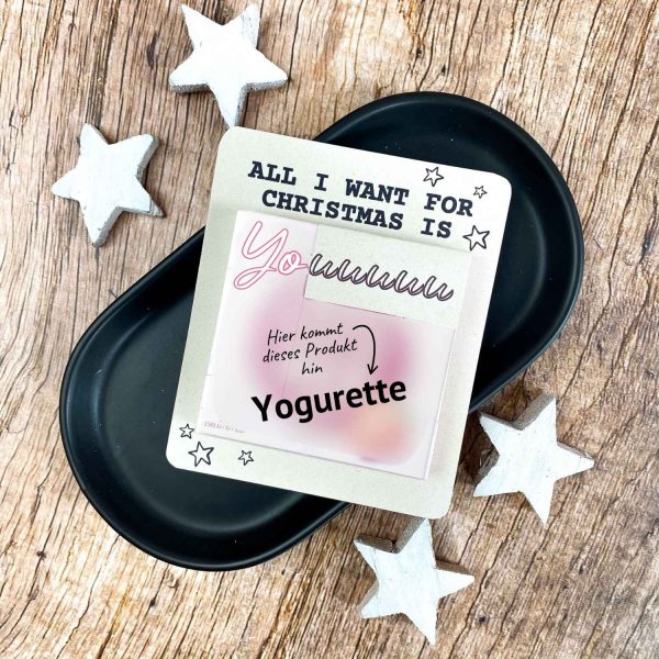Karte mit Aufschrift „All I want for Christmas is You“ und Platz für eine Yogurette-Schokolade. Liegt auf schwarzer Schale mit weißen Holzsternen. Liebevolle Druckvorlage für ein kleines Weihnachtsgeschenk zum Selbermachen.