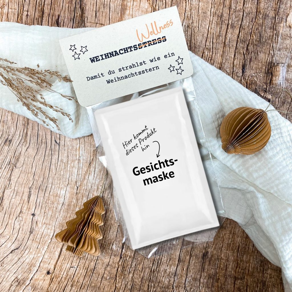DIY Druckvorlage mit dem Spruch „Wellness statt Weihnachtsstress – damit du strahlst wie ein Weihnachtsstern“. Die Karte liegt auf Holzuntergrund mit Papierdeko und Tannendeko, dazu eine Gesichtsmaske als Produktbeispiel. Perfekt als kleine Auszeit im Advent oder Weihnachtsgeschenk.