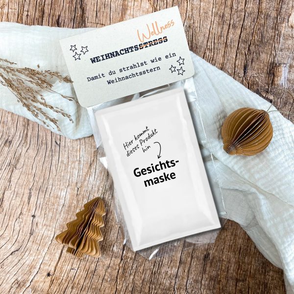 DIY Druckvorlage mit dem Spruch „Wellness statt Weihnachtsstress – damit du strahlst wie ein Weihnachtsstern“. Die Karte liegt auf Holzuntergrund mit Papierdeko und Tannendeko, dazu eine Gesichtsmaske als Produktbeispiel. Perfekt als kleine Auszeit im Advent oder Weihnachtsgeschenk.