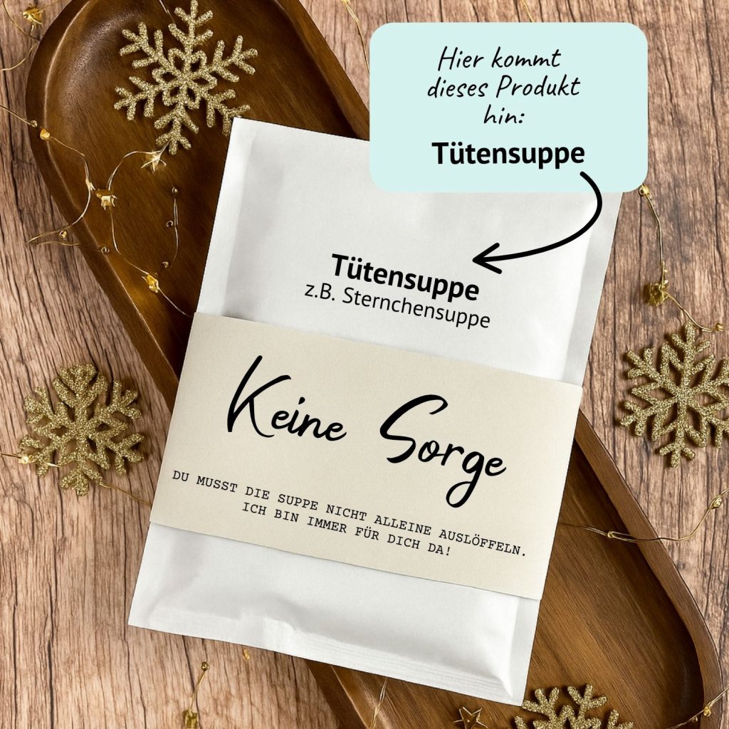 DIY Druckvorlage für eine Tütensuppe mit der Aufschrift „Keine Sorge – du musst die Suppe nicht alleine auslöffeln“. Die Suppe steckt in einer liebevoll gestalteten Banderole, umgeben von Holzdeko und goldenen Schneeflocken. Humorvolle Geschenkidee zum Ausdrucken.